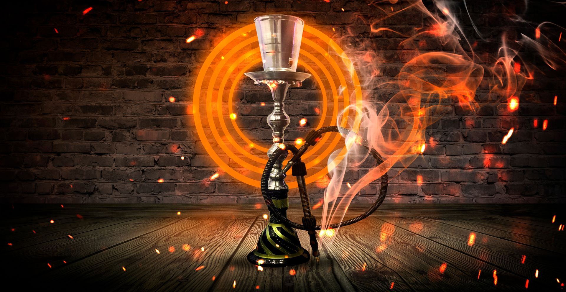 A hookah is sitting on a wooden floor in front of a brick wall.