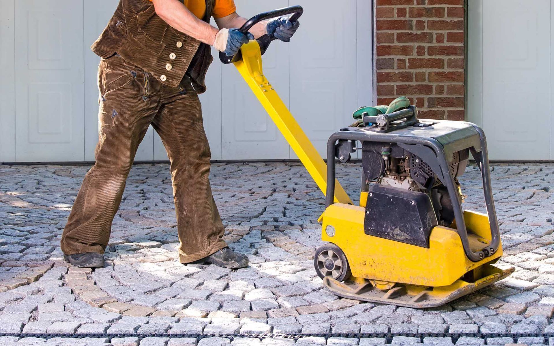 local contractor using a compacting machine to settle the pavers