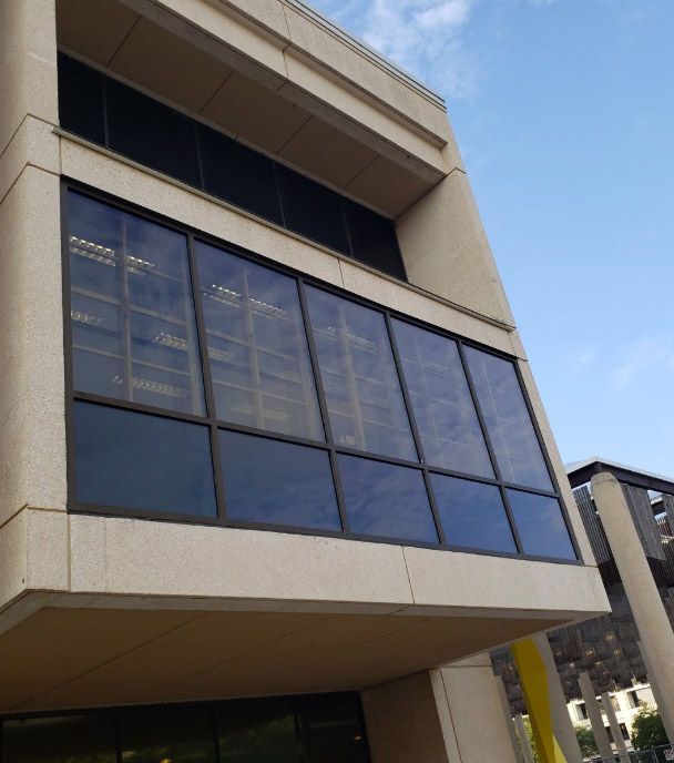 UTSA John Peace Library with large dark glass windows and beige concrete facade under a blue sky