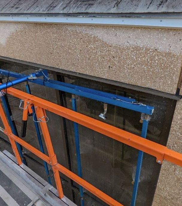 Blue and orange scaffolding in front of a building window under repair