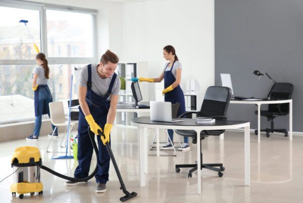 A man is using a vacuum cleaner to clean an office.