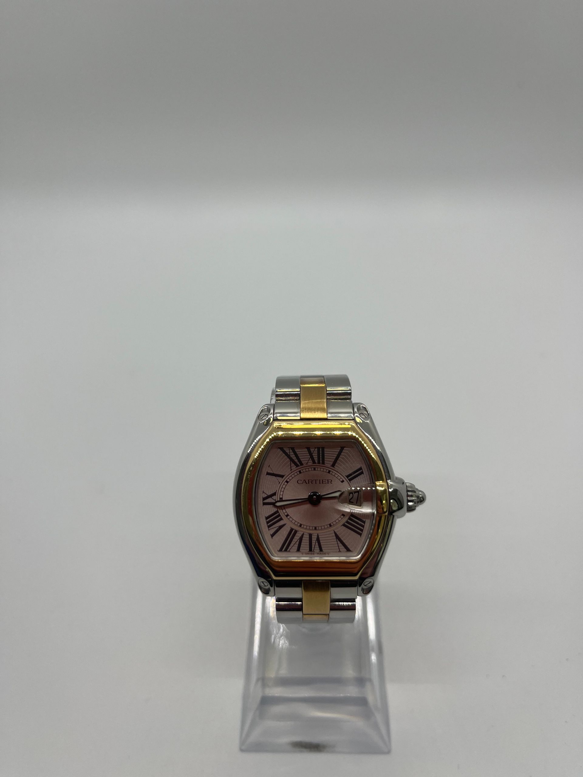 Two-tone wristwatch on clear stand against white background.