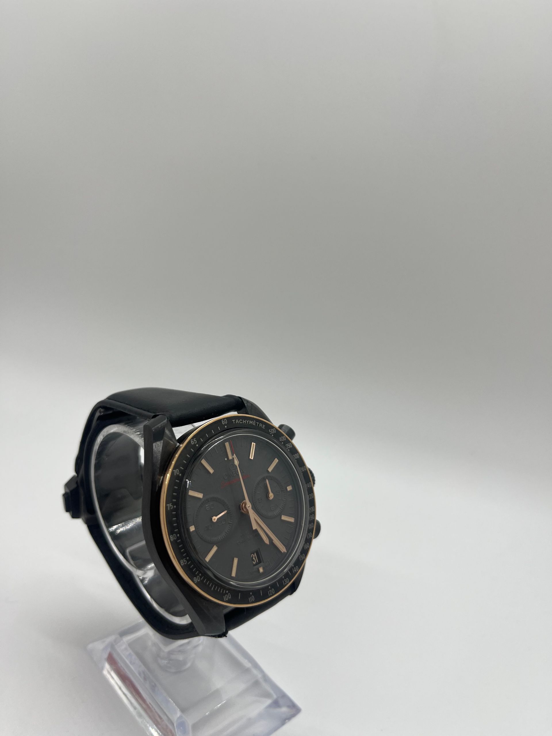 Black wristwatch on a clear stand against a white background.