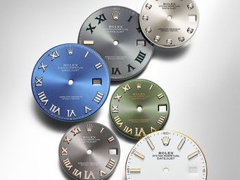 A group of clock faces are sitting on top of each other on a table.