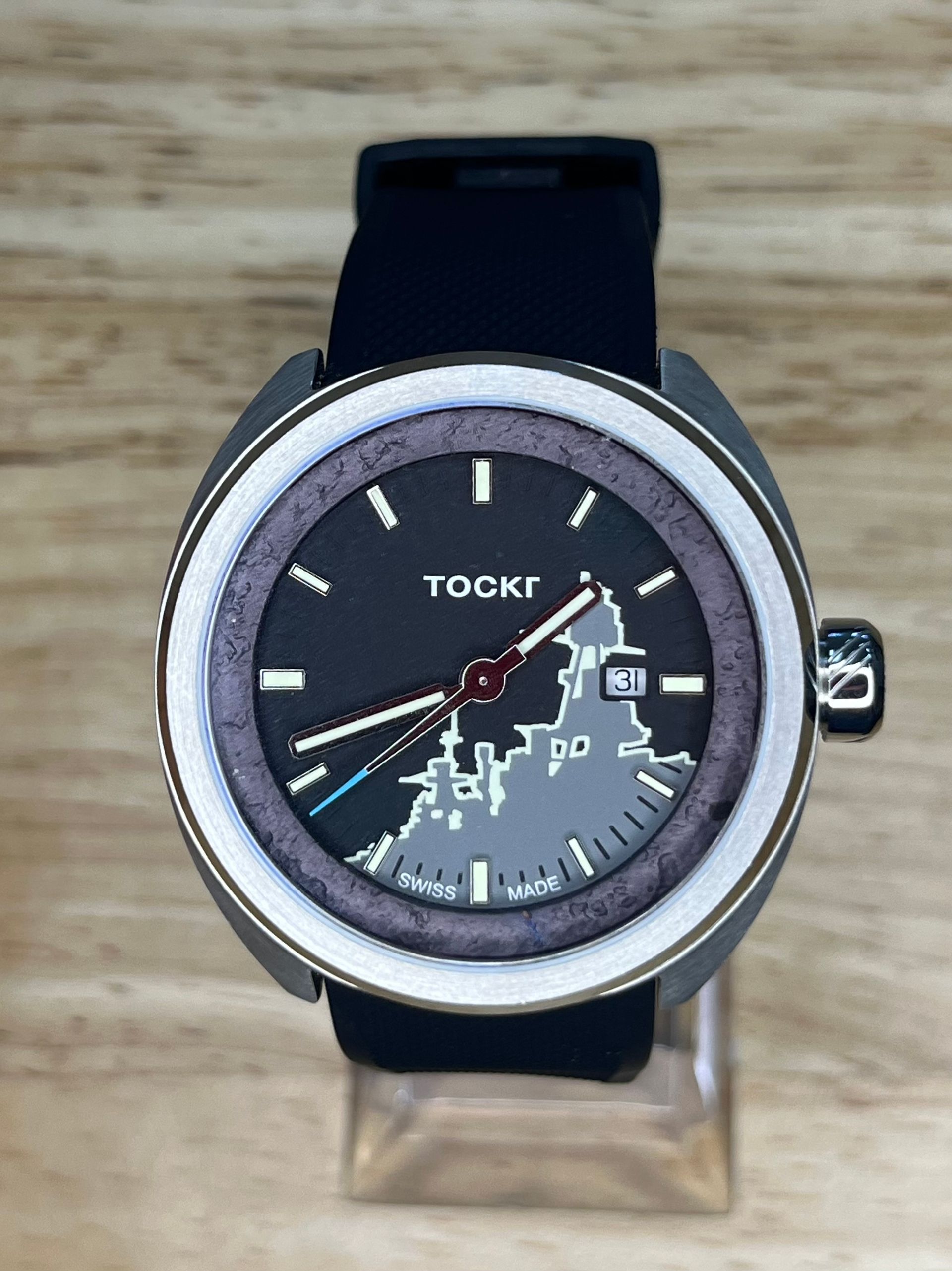 Watch with a map design on the face, set on a black band. The face is black, with a gray and white world map.