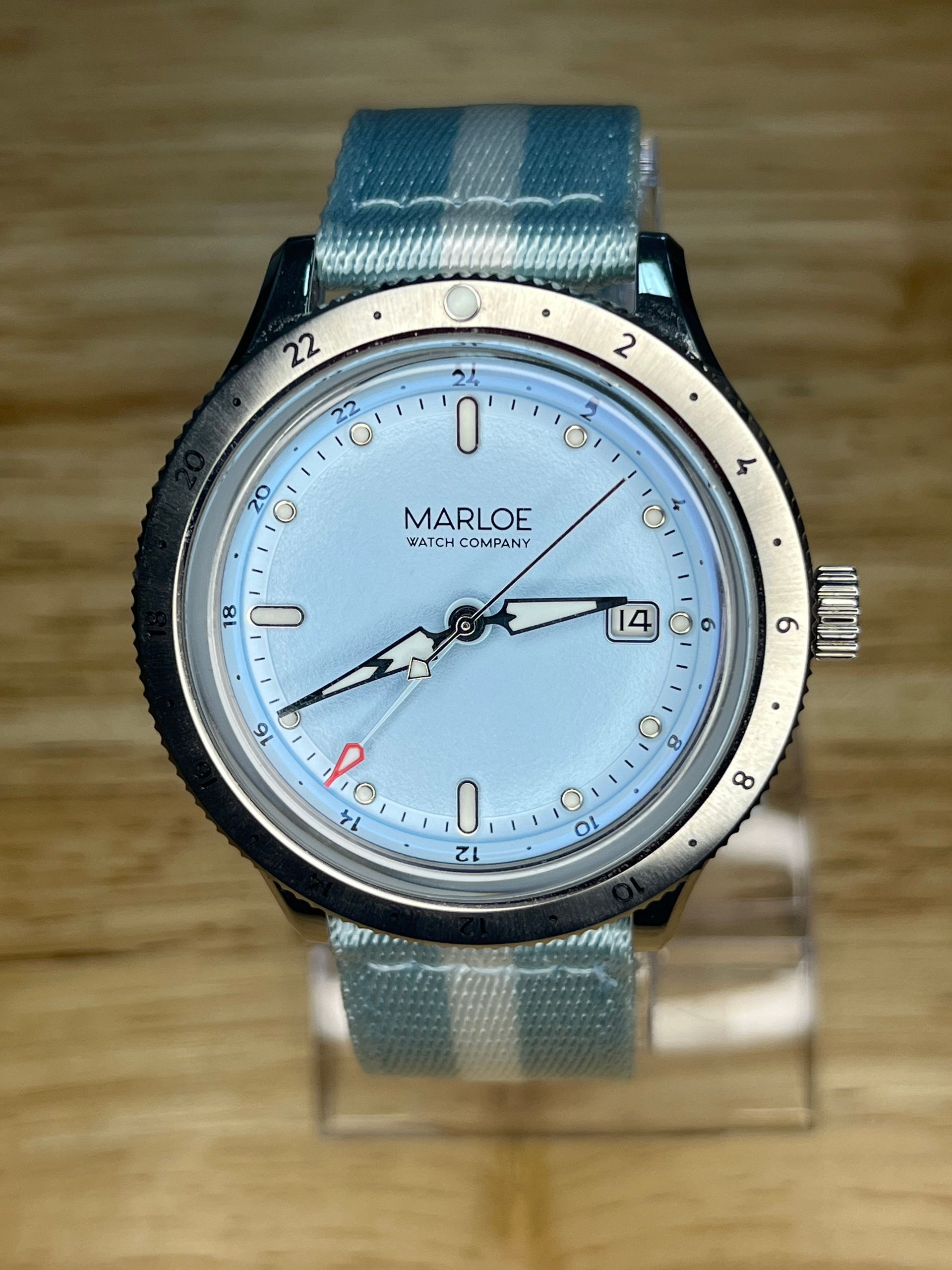 Light blue watch with matching striped band, black bezel, and a light blue face.