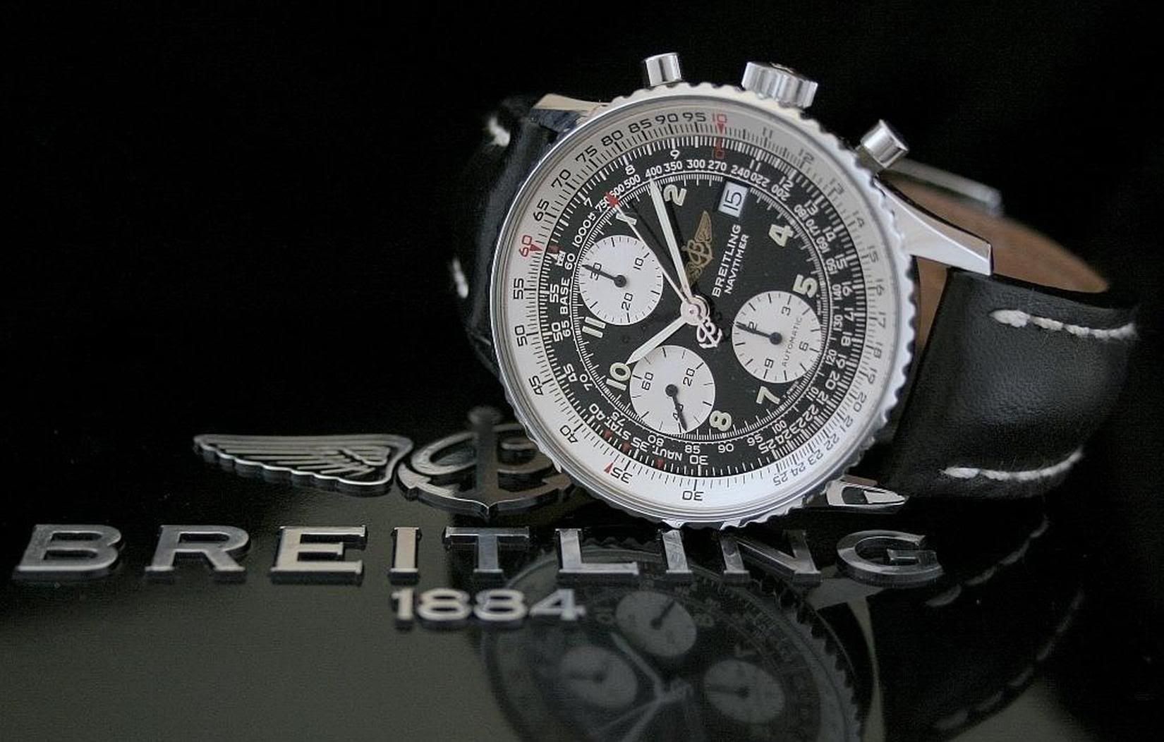 Breitling Navitimer watch on a reflective black surface with the Breitling logo.
