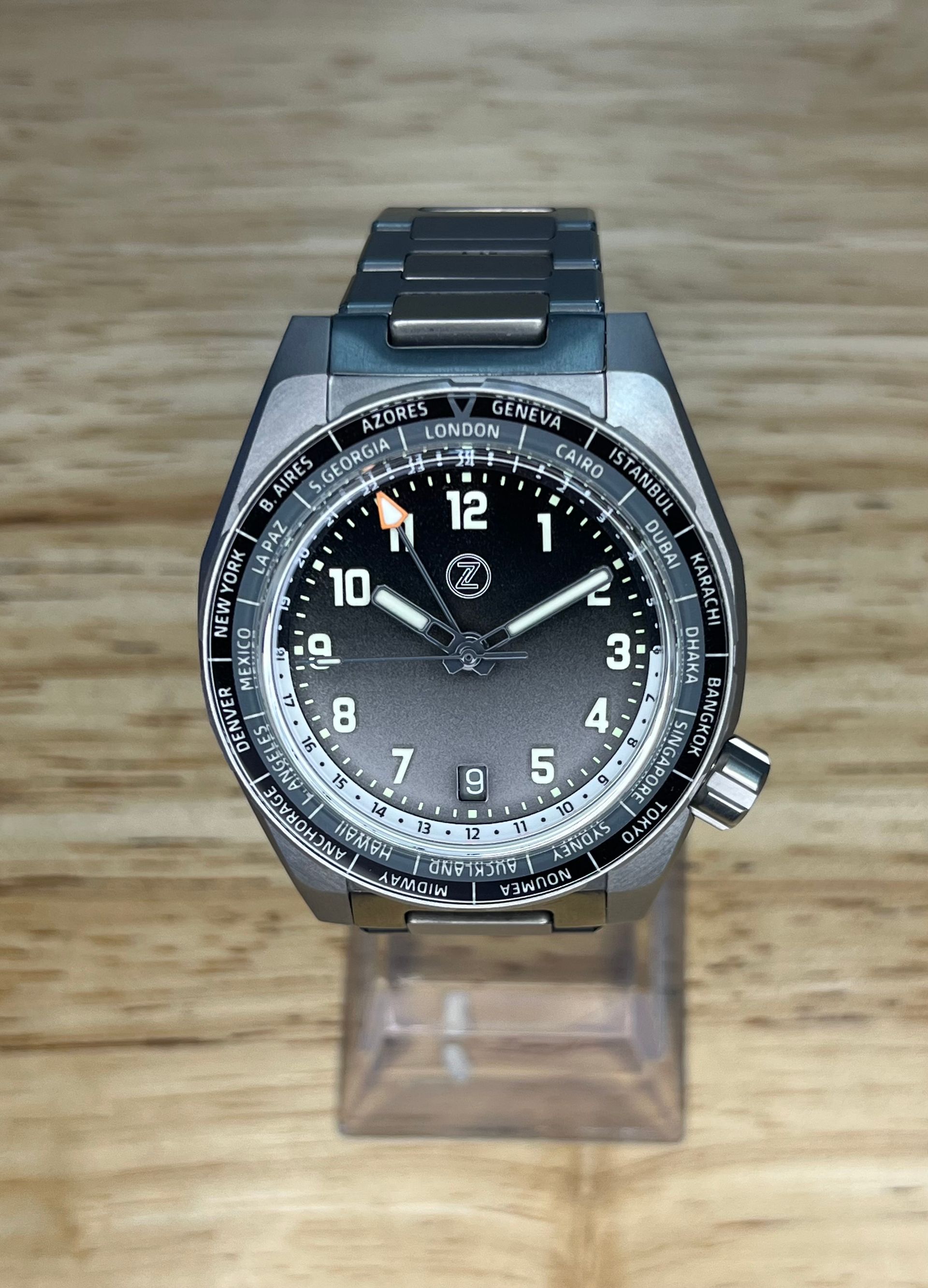 Titanium wristwatch with a dark dial, world time bezel, and silver band.