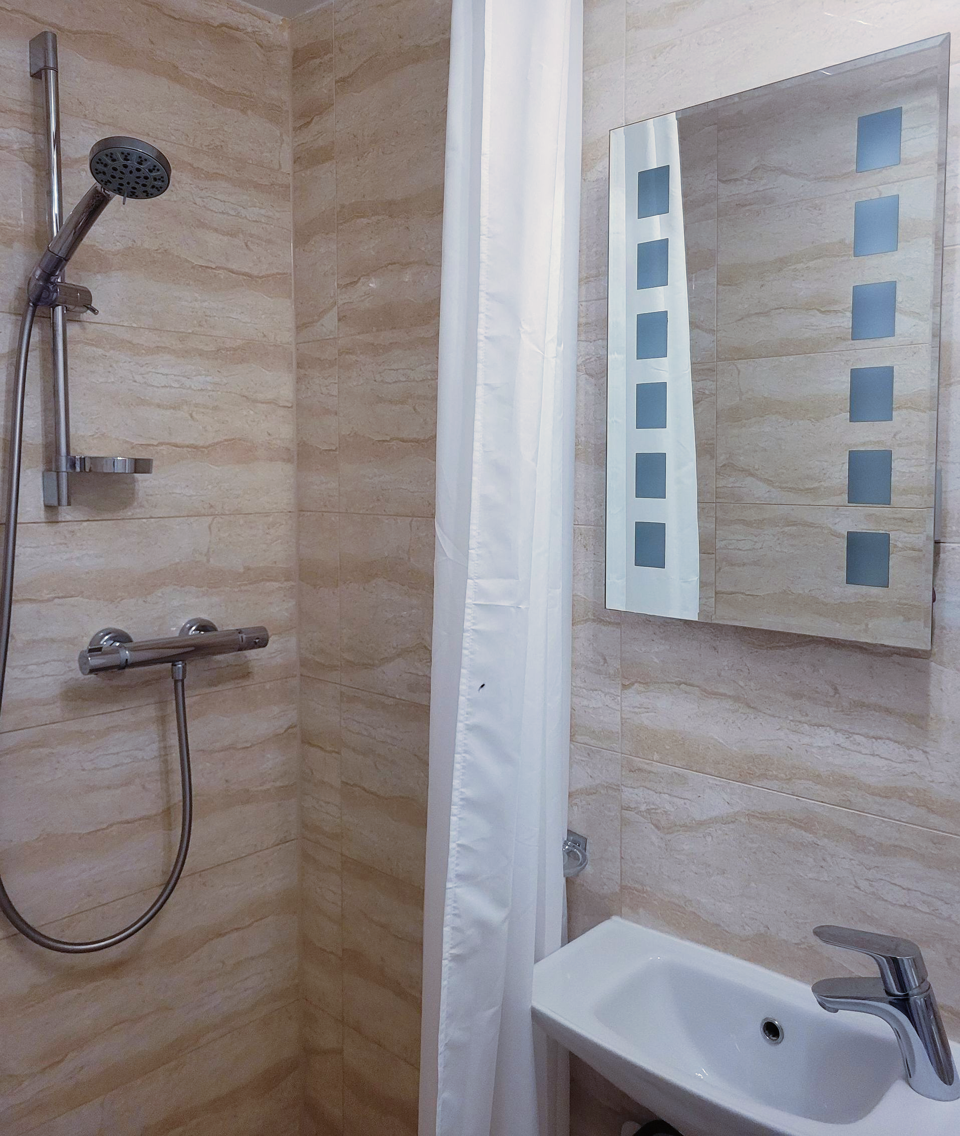 A bathroom with a sink a shower and a mirror