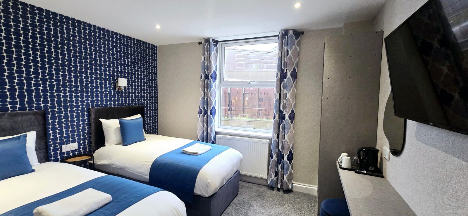 A hotel room with two beds and blue blinds.
