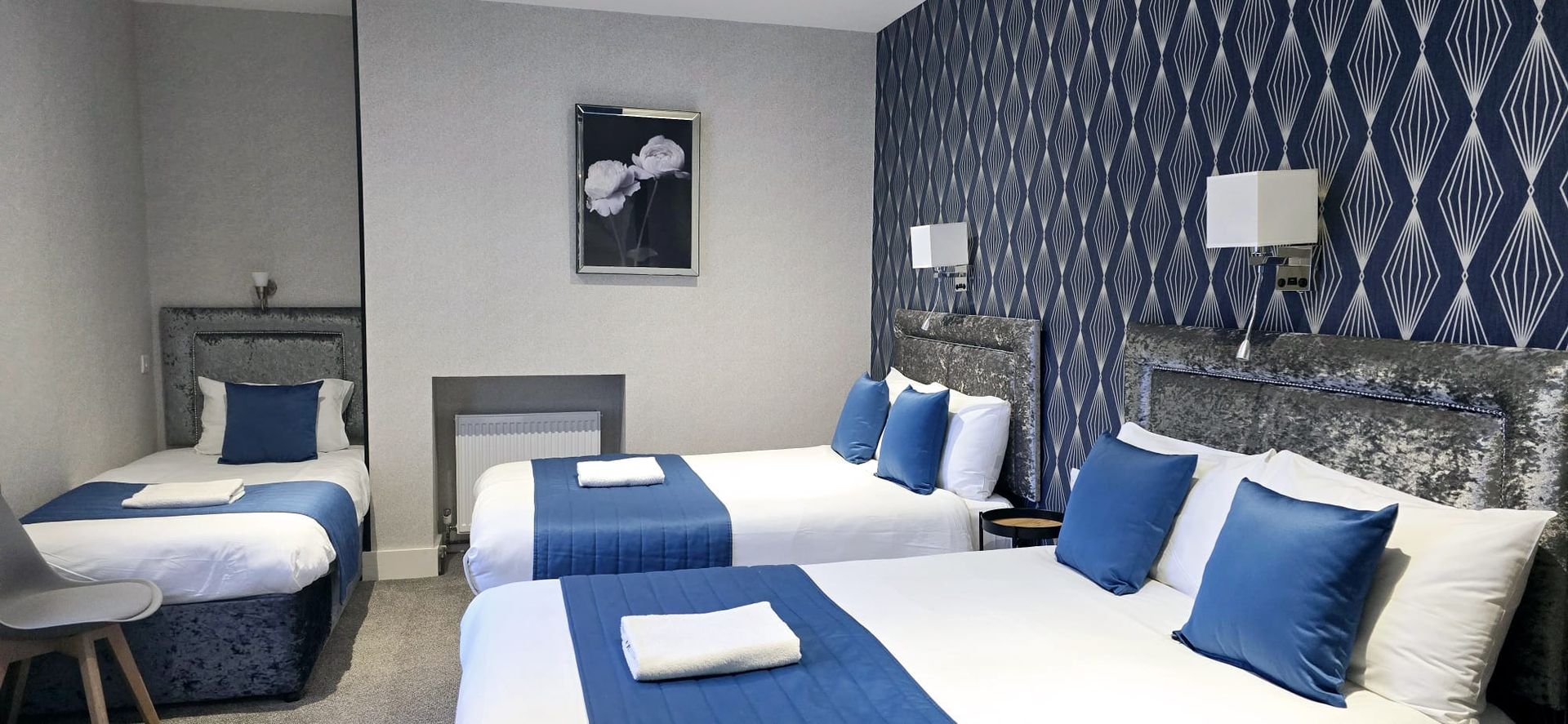 A hotel room with three beds and a picture on the wall