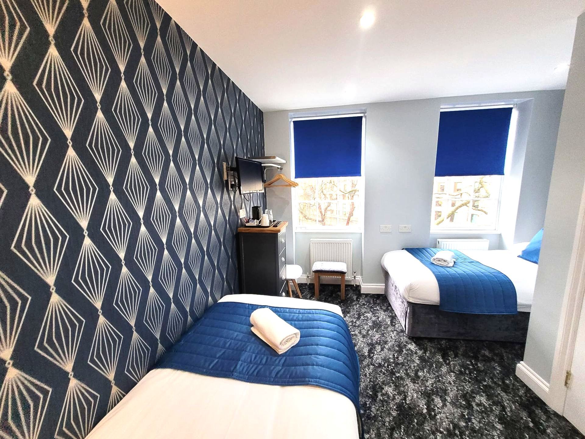 A hotel room with two beds and blue blinds.