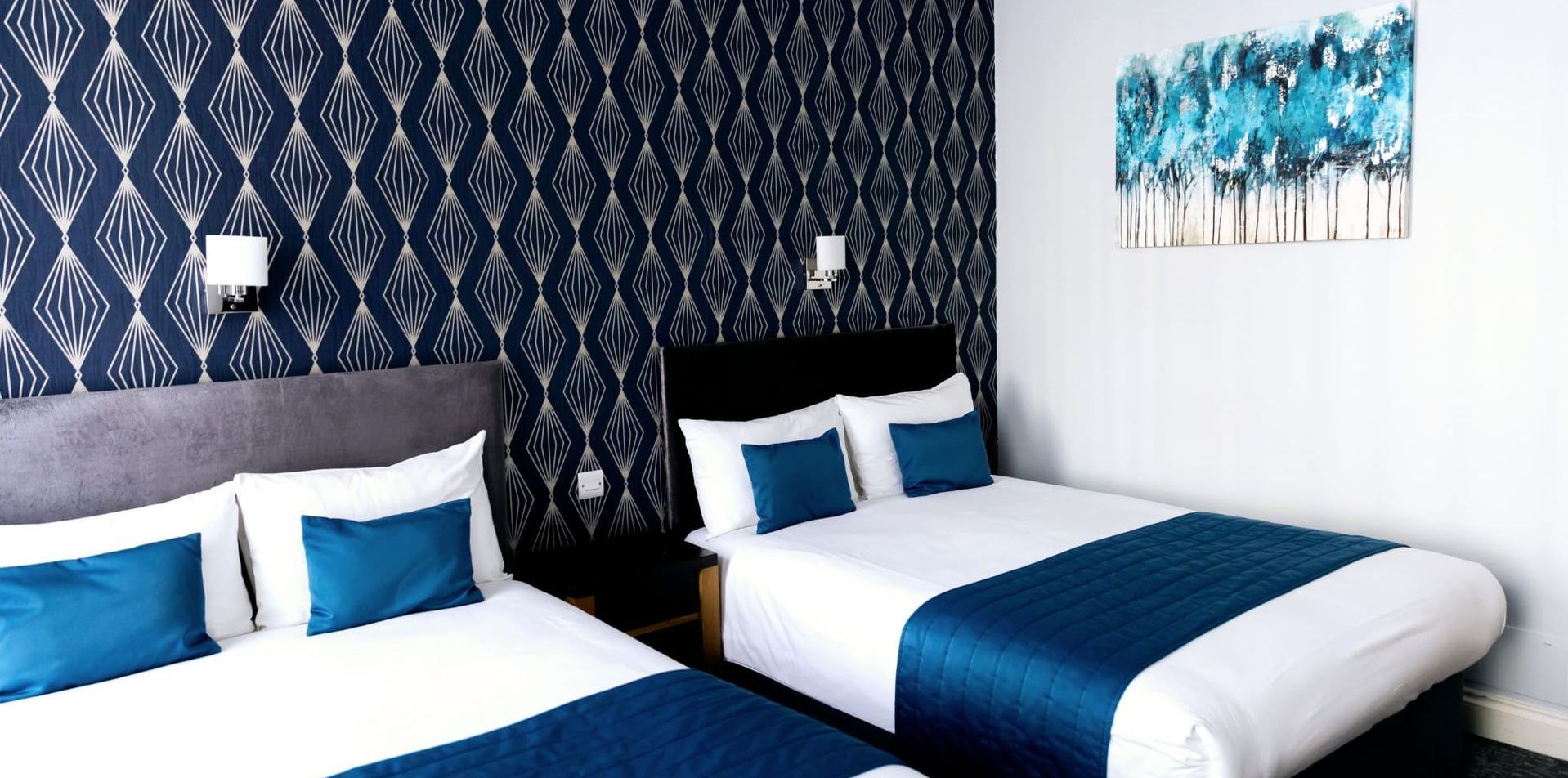 A hotel room with two beds and a painting on the wall