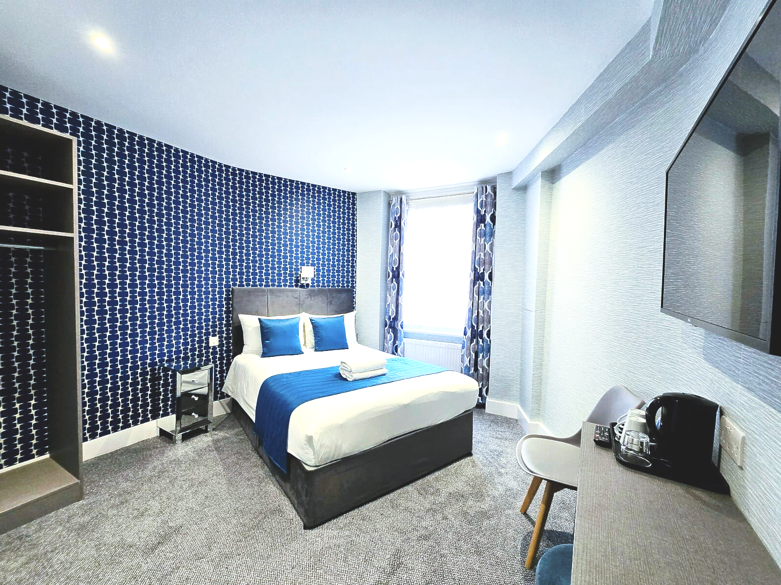 A hotel room with a king size bed and a flat screen tv.