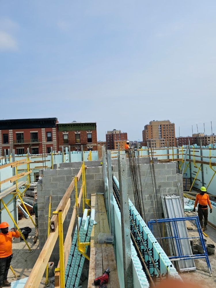 Construction site with workers on an unfinished concrete building and scaffolding under a cloudy sky
