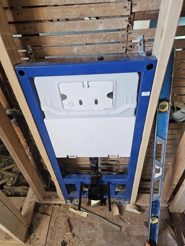 Blue-framed toilet tank installed in exposed bathroom floor framing, viewed from below