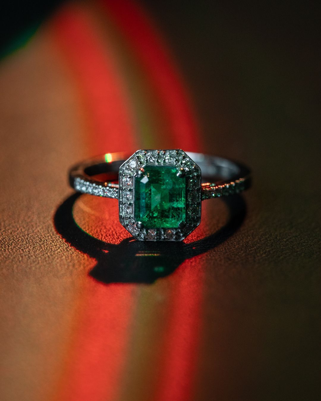 Primo piano di un anello con smeraldo e diamanti su un tavolo.