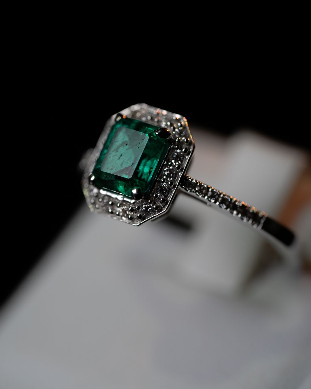 Un primo piano di un anello con uno smeraldo e diamanti