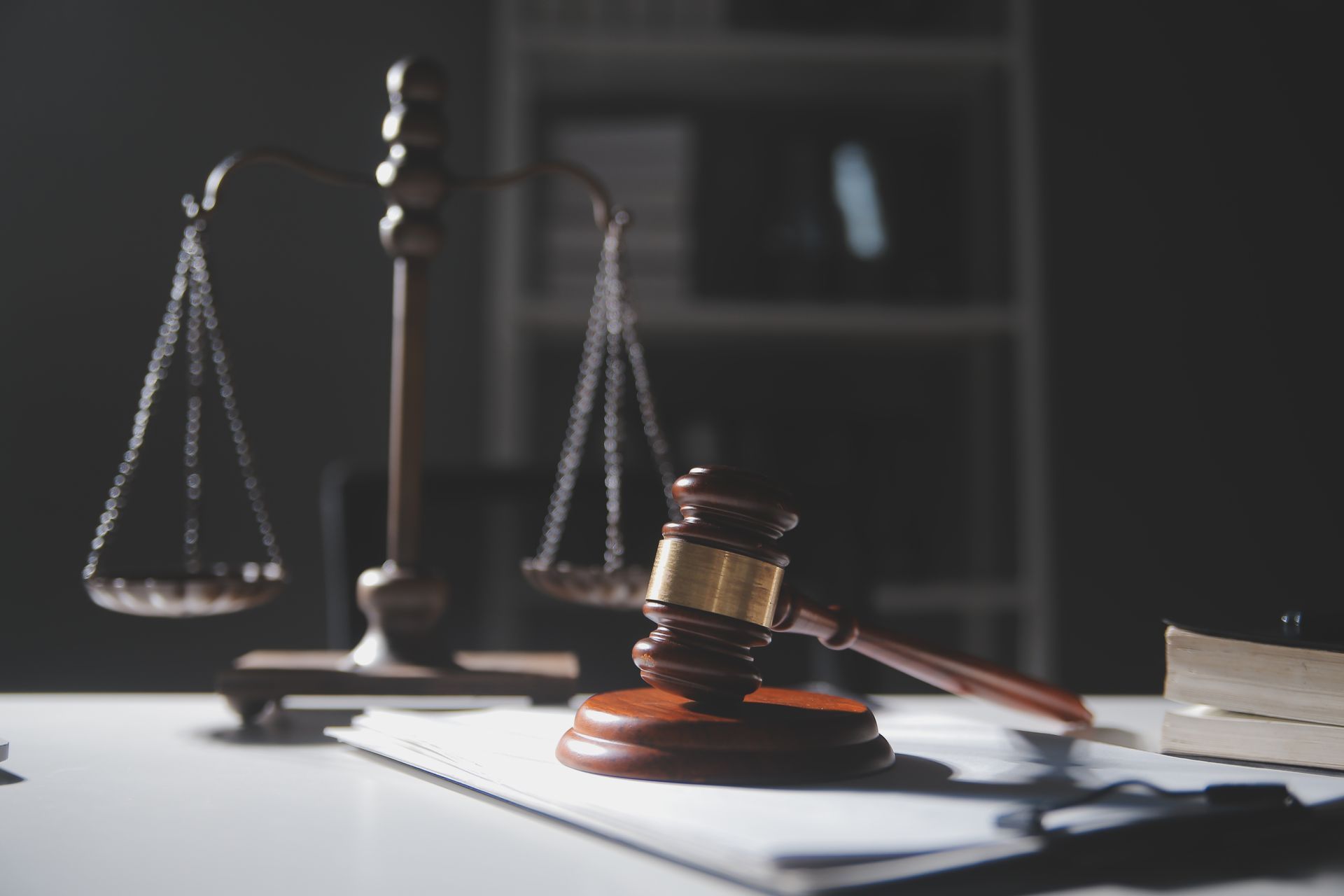 Judge's gavel on papers with scales of justice in a dim courtroom setting