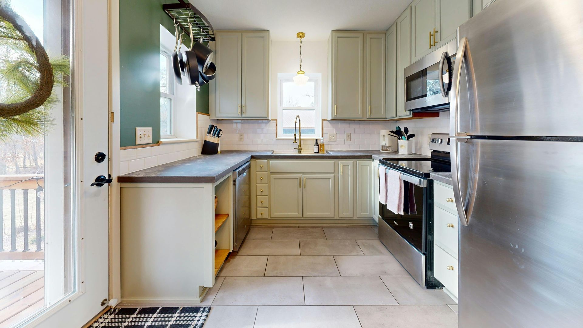 Bright modern kitchen with stainless steel appliances, light cabinets, and a narrow walkway
