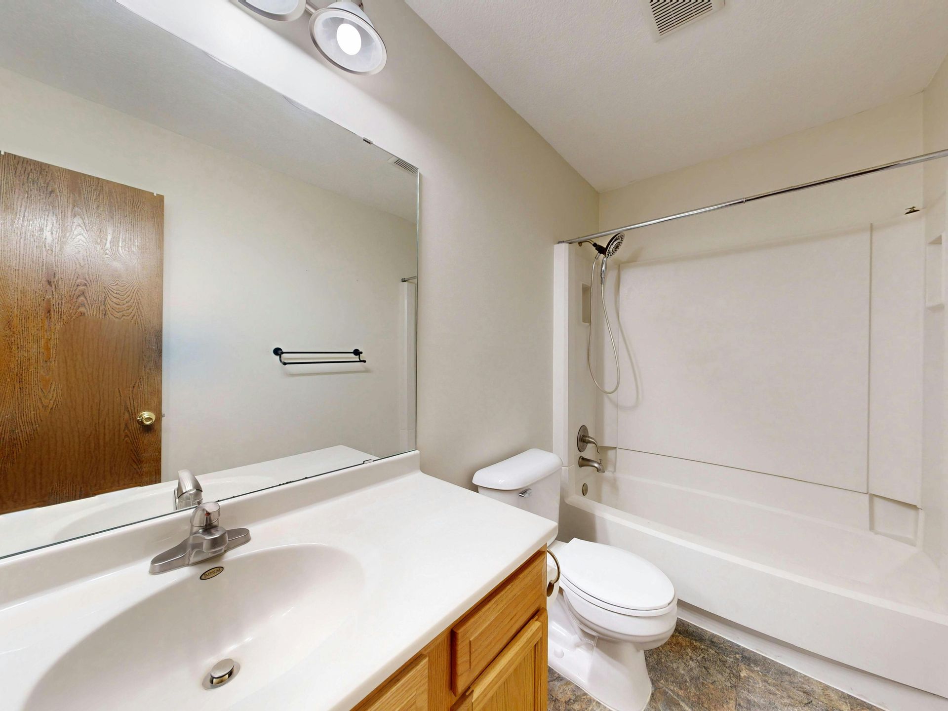 Bathroom with white vanity, mirror, toilet, and bathtub with shower curtain