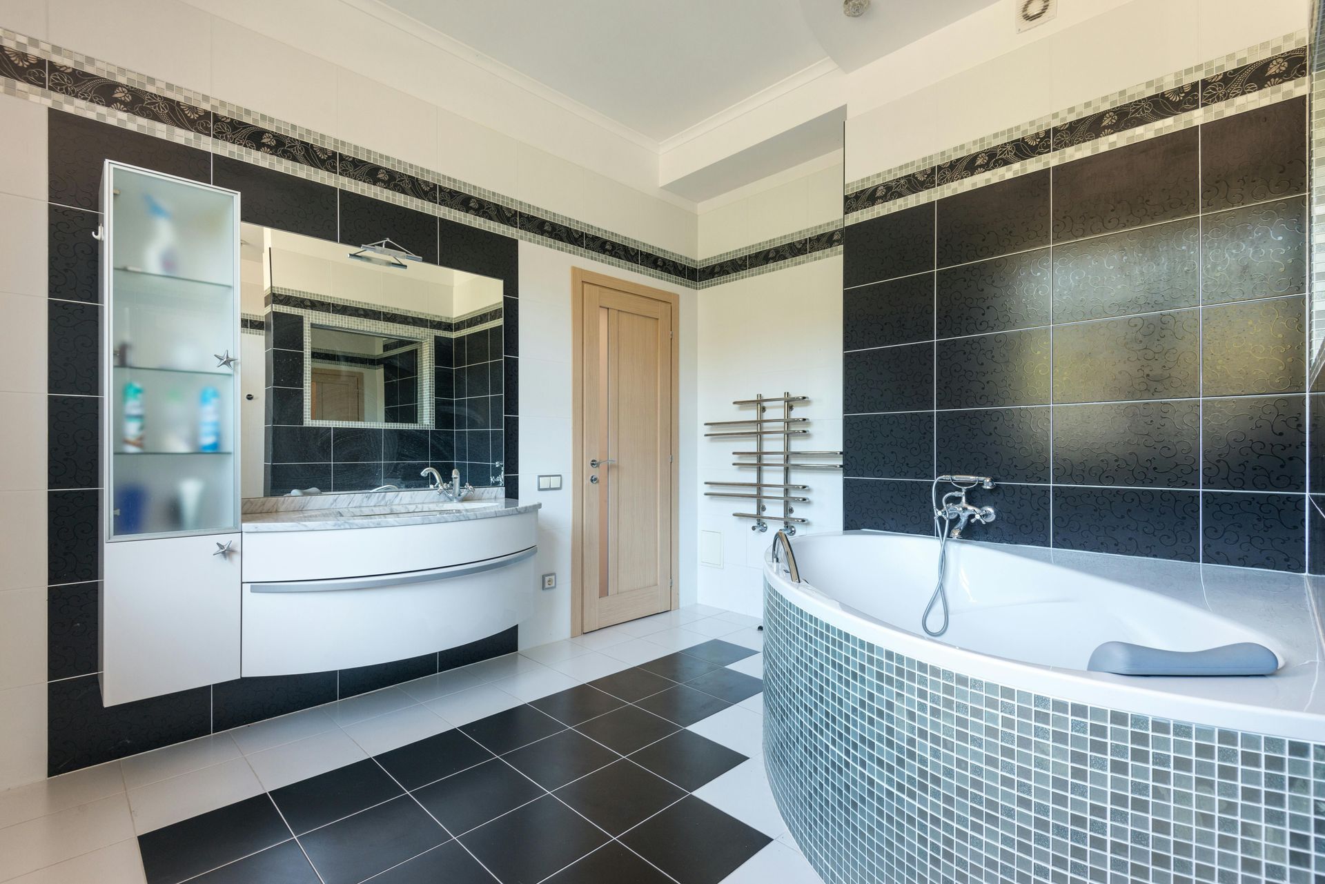 Modern black-and-white bathroom with double vanity, large mirror, and tiled bathtub area