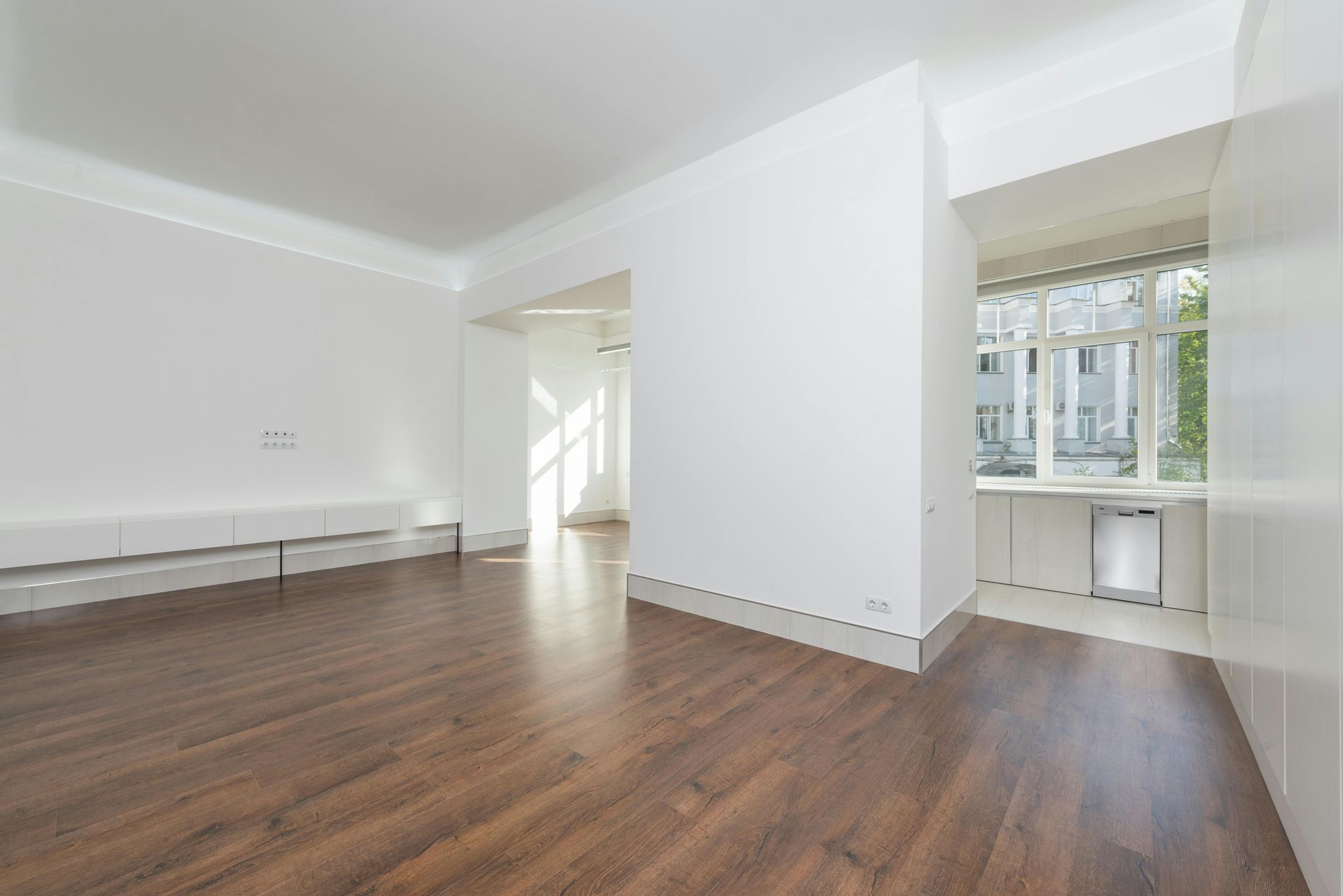 Empty white room with wood floors, bench, and large window nook