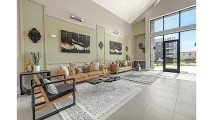 Burleson Electrician - Modern lounge area with wooden furniture, patterned rugs, and abstract art. Large windows and neutral tones create an open, inviting atmosphere.