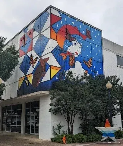 Burleson Electrician - Mural featuring a stylized woman with blue hair and monarch butterflies covering the side of a modern white building.