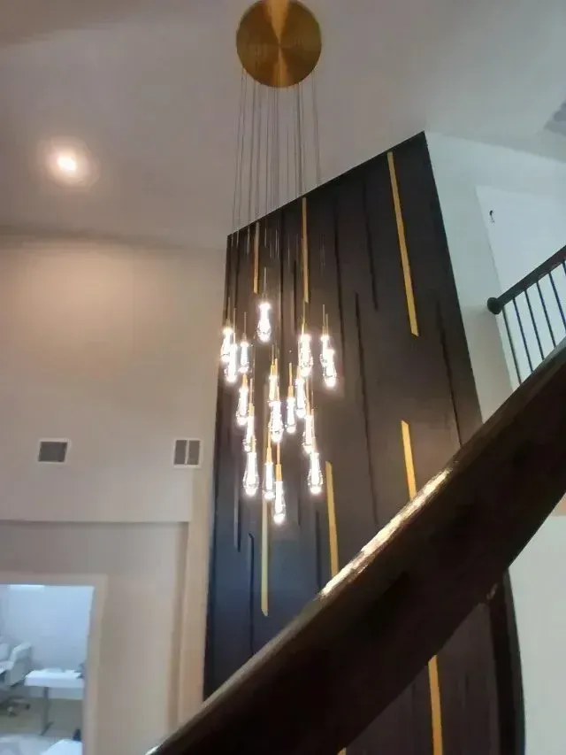 Burleson electrician -  professionals provide expert lighting installation services, as showcased by this elegant modern chandelier hanging in a high-ceilinged stairwell.