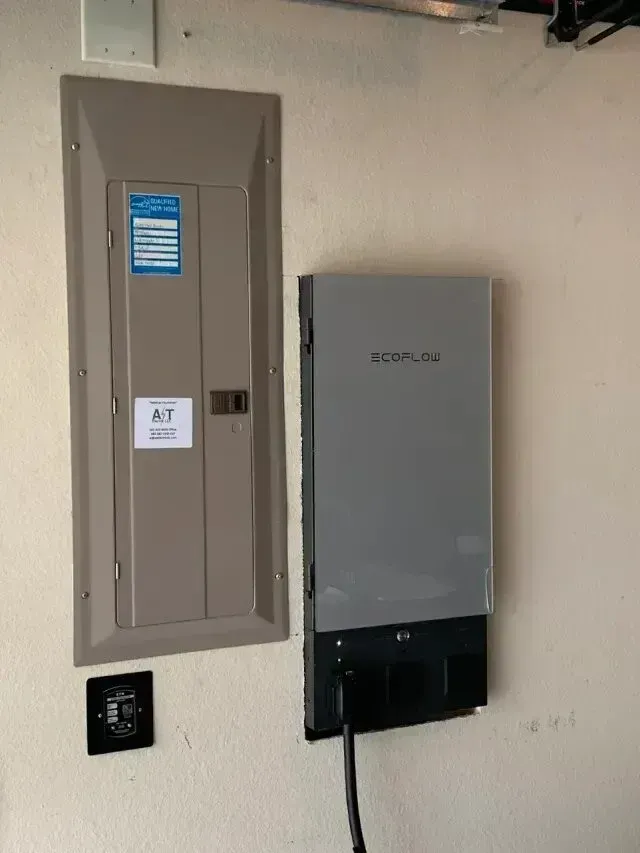 Burleson electrician - A wall-mounted EcoFlow inverter next to an electrical panel, with a control panel below and a power cable connected.