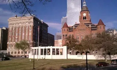 Burleson Electrician - Historic red brick courthouse and a grand hotel next to modern high-rise, under a clear blue sky, with green lawns and trees in the foreground.