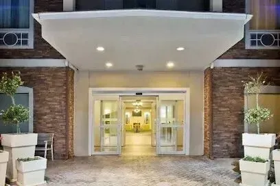 Burleson Electrician - Entrance to a modern building with sliding glass doors, flanked by tall potted plants. Warm lighting creates an inviting, welcoming ambiance.