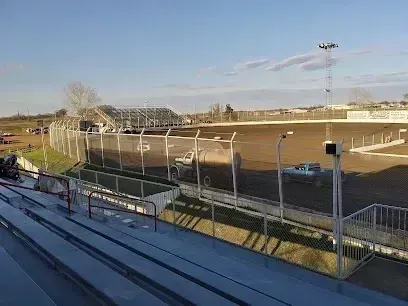 Burleson Electrician - View from the grandstands overlooking a dirt racetrack enclosure with a white fence, parked trucks, and stadium lights under a bright sky.