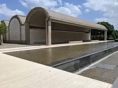 Burleson Electrician - Modernist building with barrel-vaulted roofs next to a long, rectangular reflecting pool with a small waterfall edge.