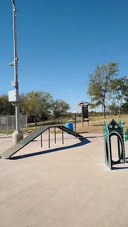 Burleson Electrician - A sunny day at an outdoor dog park featuring a ramp and agility hurdles. Trees and a clear blue sky create a peaceful and inviting atmosphere.