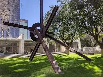 Burleson Electrician 
- Large metal sculpture with intersecting beams sits on a grassy lawn near modern glass buildings and leafy trees.