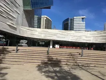 Burleson Electrician 
- Wide view of a modern architectural museum entrance with slanted gray walls and tiered steps. Background includes tall city buildings under a clear blue sky.
