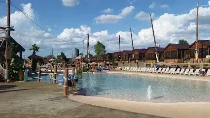 Burleson Electrician - Sunny day at a water park with a large, empty shallow pool surrounded by sun loungers and tiki-style huts.
