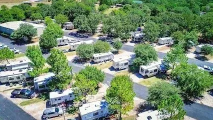 Burleson Electrician -Aerial view of a sunny RV park with neatly arranged RVs among green trees. The scene conveys tranquility and outdoor recreation.