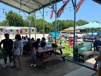 Burleson Electrician -Entrance archway to Chisenhall Fields with text on top, surrounded by manicured lawns and a bright blue sky with clouds.