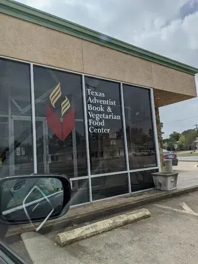 Burleson Electrician 
- Exterior of a store with large windows displaying “Texas Adventist Book & Vegetarian Food Center.” A cloudy sky reflects on the glass, conveying a calm atmosphere.
