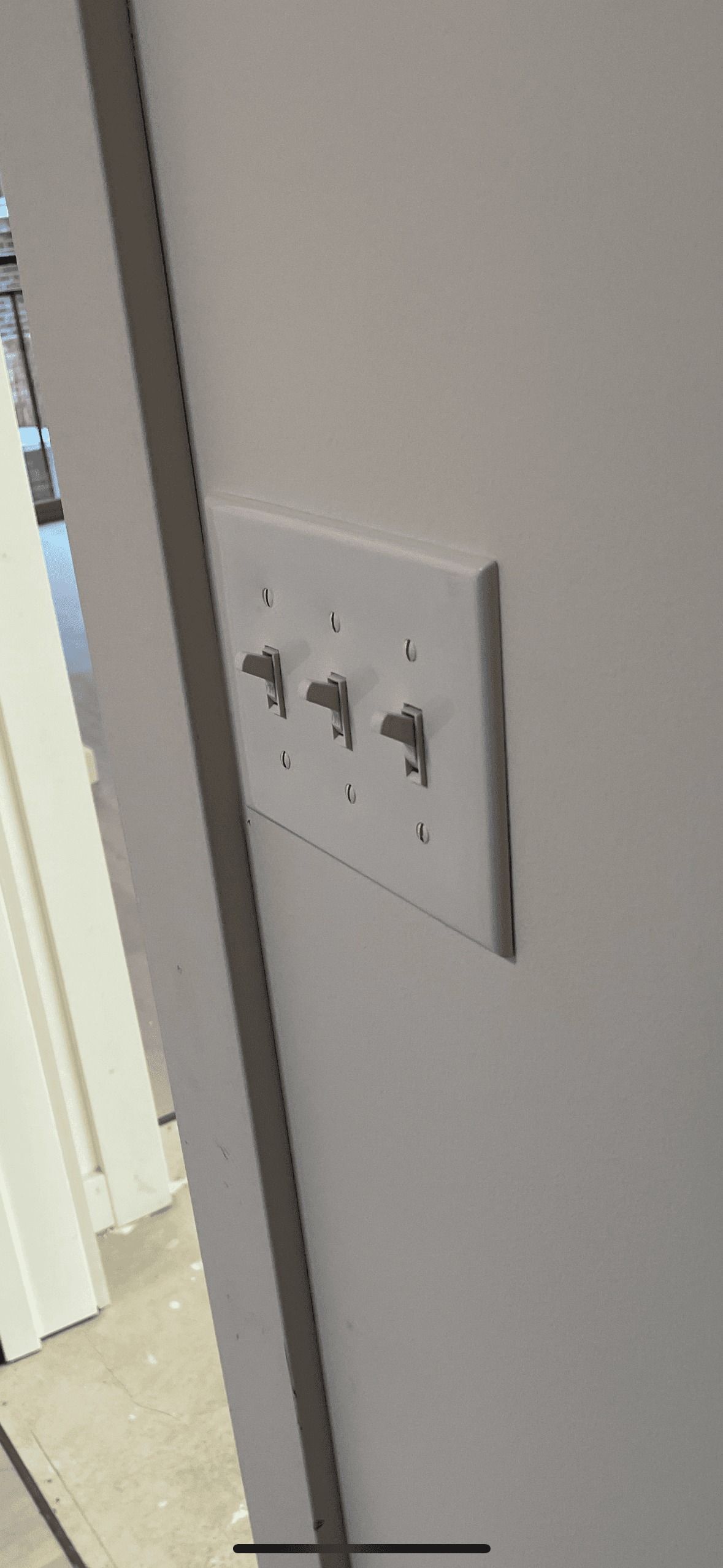 White wall with a light switch plate, three toggle switches visible.