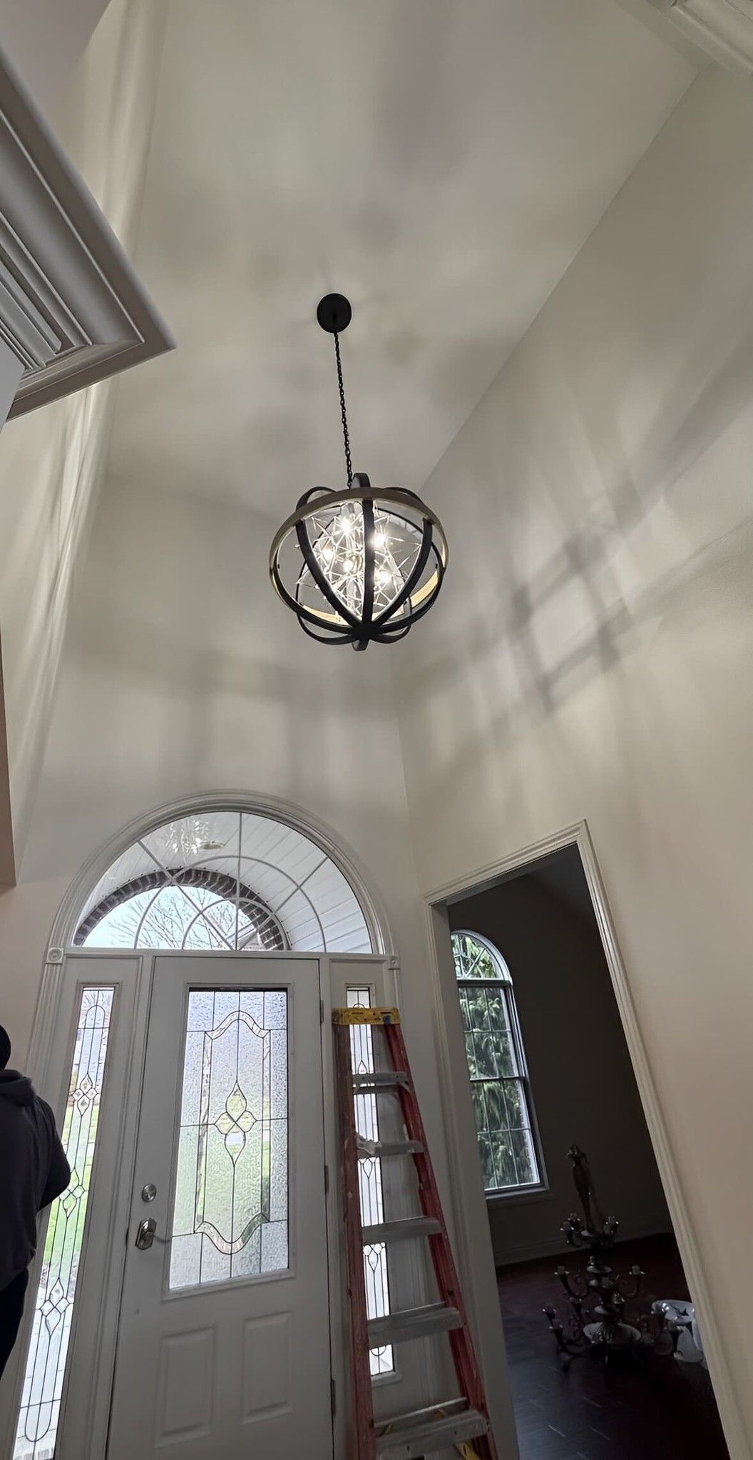Entryway with a decorative globe light fixture, arched doorway, and ladder.