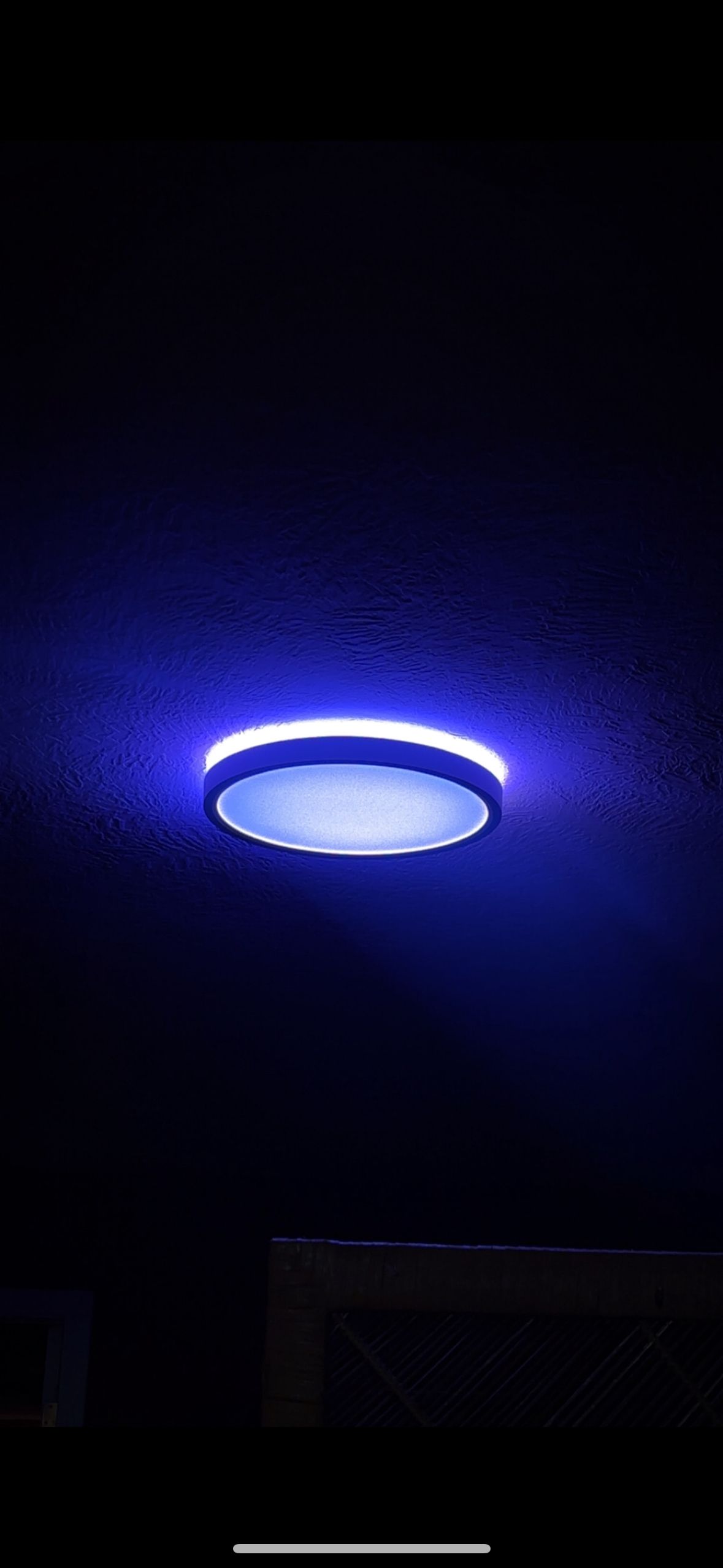 Blue, circular light fixture on a dark ceiling.
