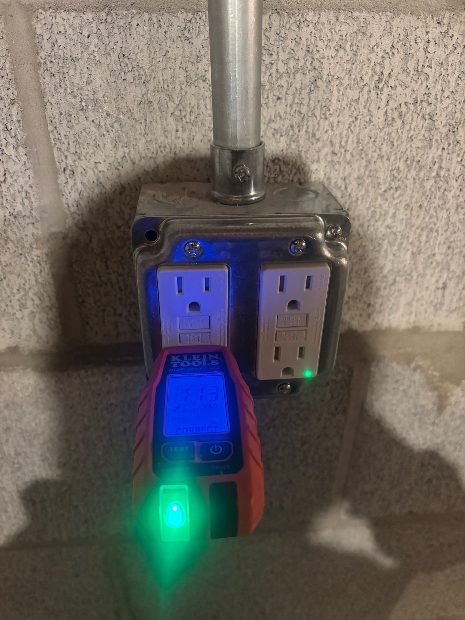 Outlet tester plugged into an electrical outlet; green lights indicate correct wiring.