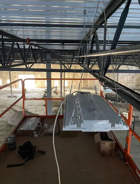 Construction site with overhead beams, a platform, and a large metal object suspended.