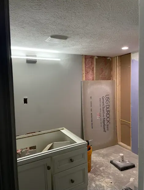 Bathroom renovation in progress, featuring a vanity, exposed framing, and shower wall construction.