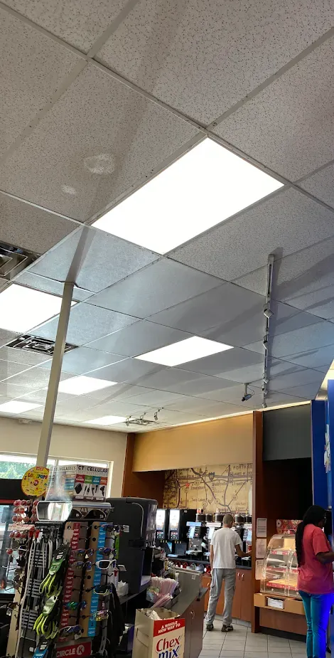 Interior of a convenience store with customers and merchandise. Fluorescent lights on the ceiling.