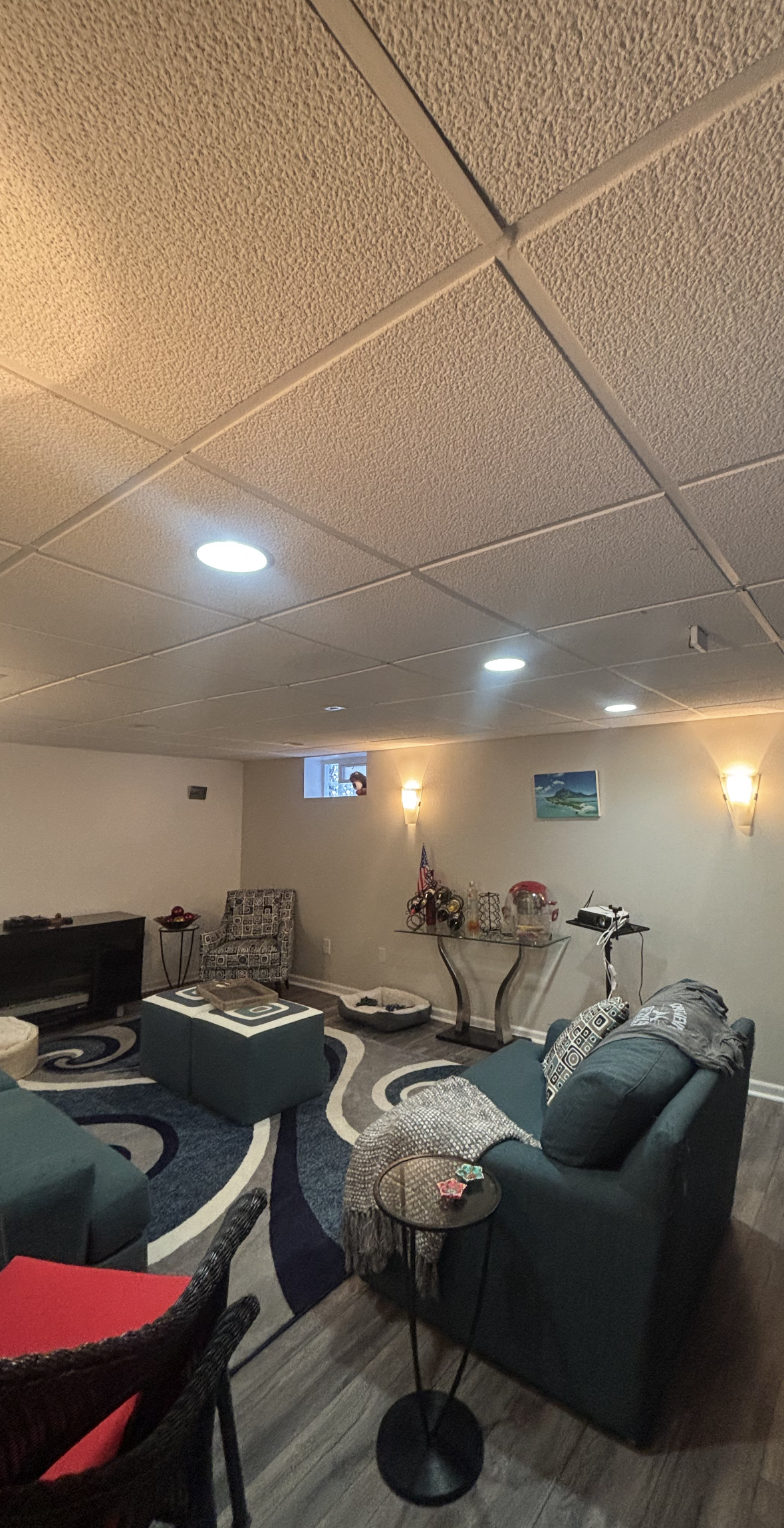 A living room with blue couches, a patterned rug, and a textured ceiling.